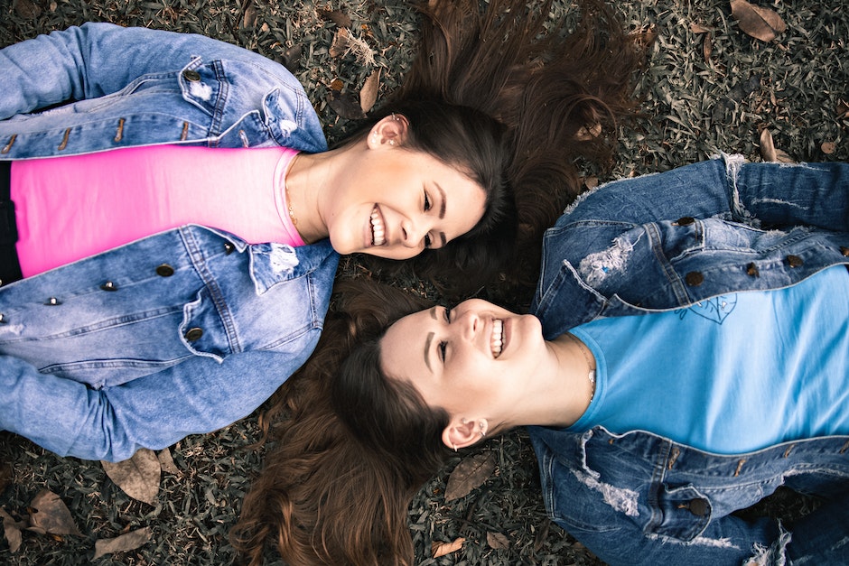 Joyful young sisters lying on ground and smiling