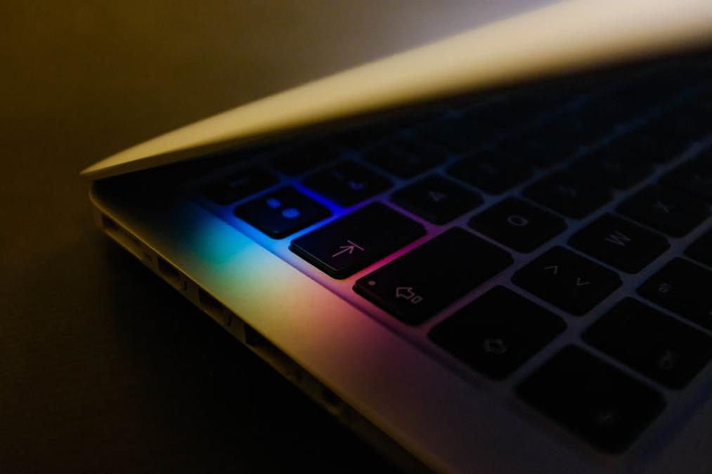a laptop computer with a colorful light on it - rainbow keys