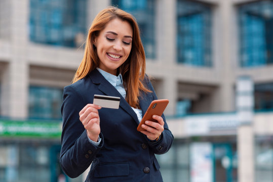 Business woman holding phone and using credit card